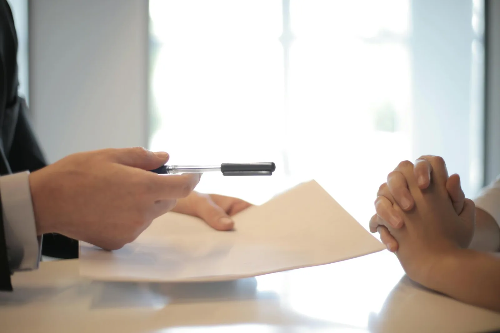 Hands with insurance paperwork and pen in a business meeting setting