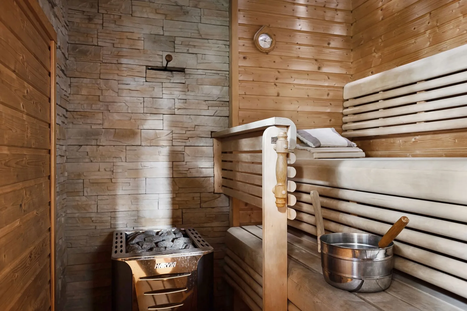 Interior view of a wooden sauna with heater, bench, and bucket